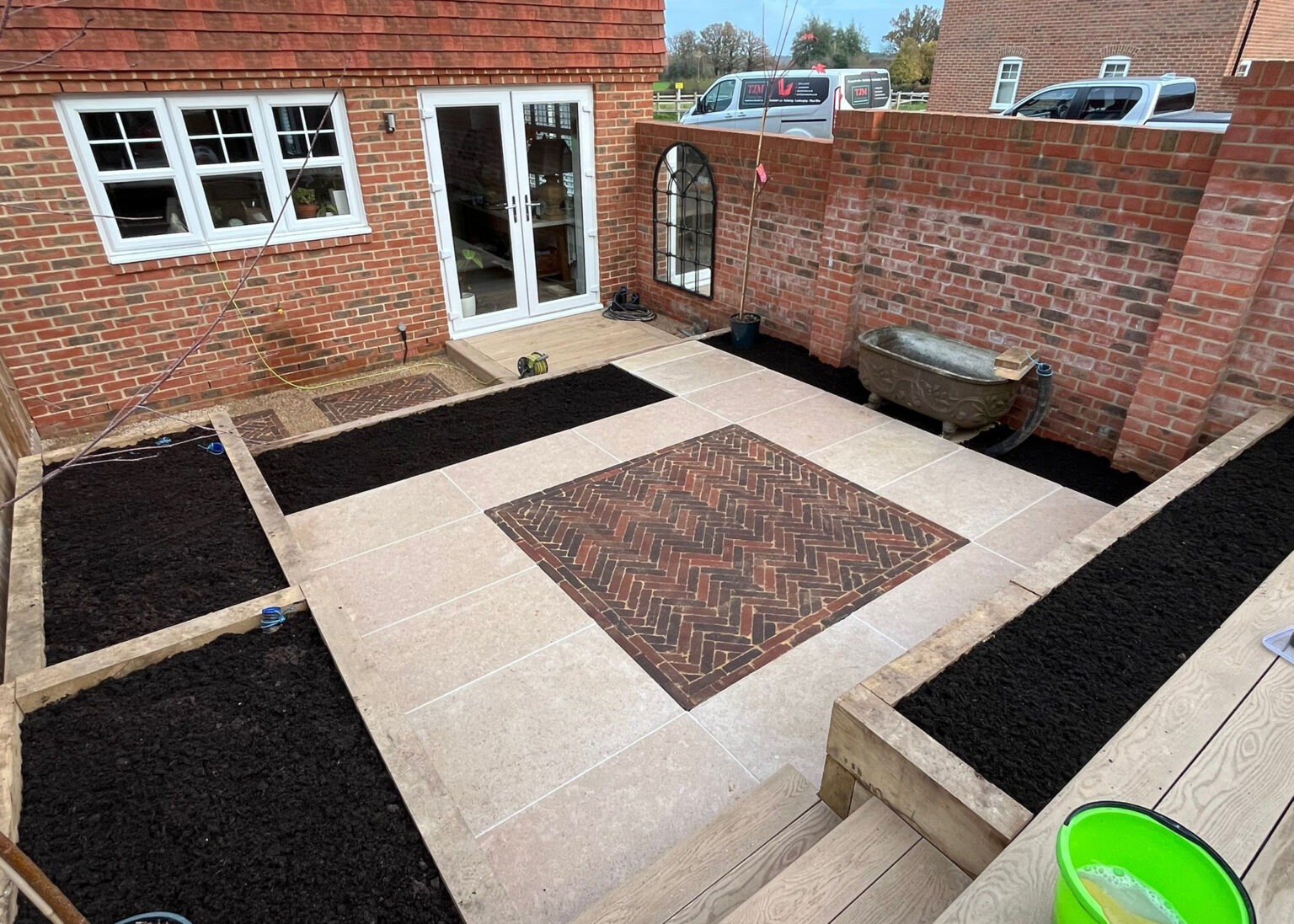 Courtyard patio with porcelain paving, brick inset detail and raised beds