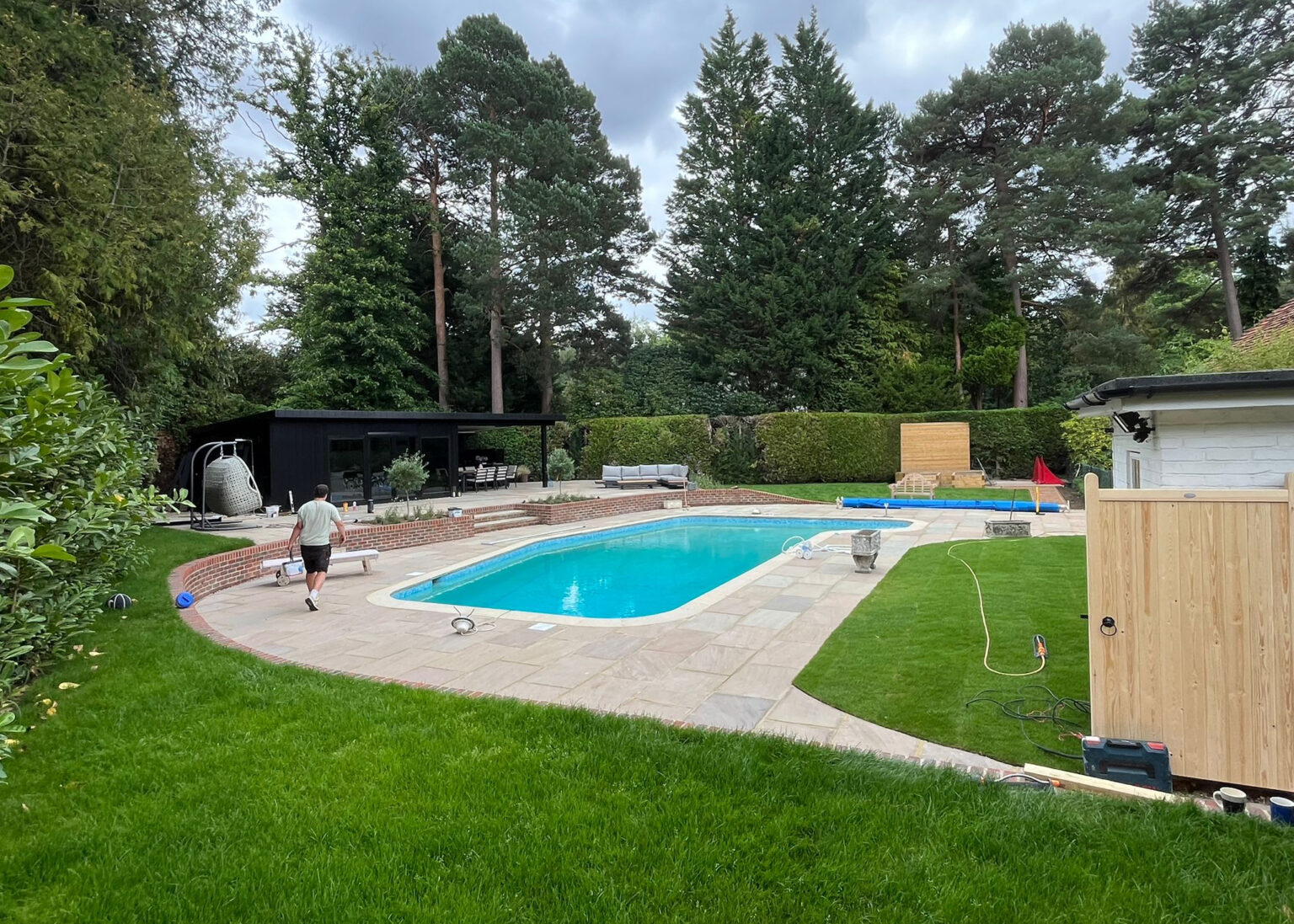 Landscaped garden with swimming pool, large patio and lawn installation in Surrey