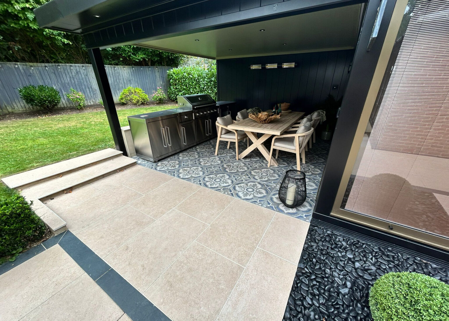 Outdoor kitchen and covered seating area with tiled flooring and patio steps