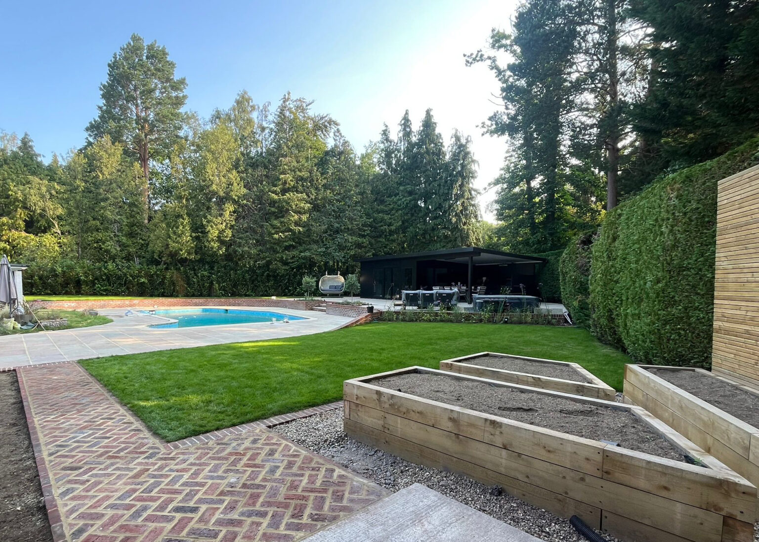 Landscaped garden with lawn, raised beds and pool patio installation in Surrey