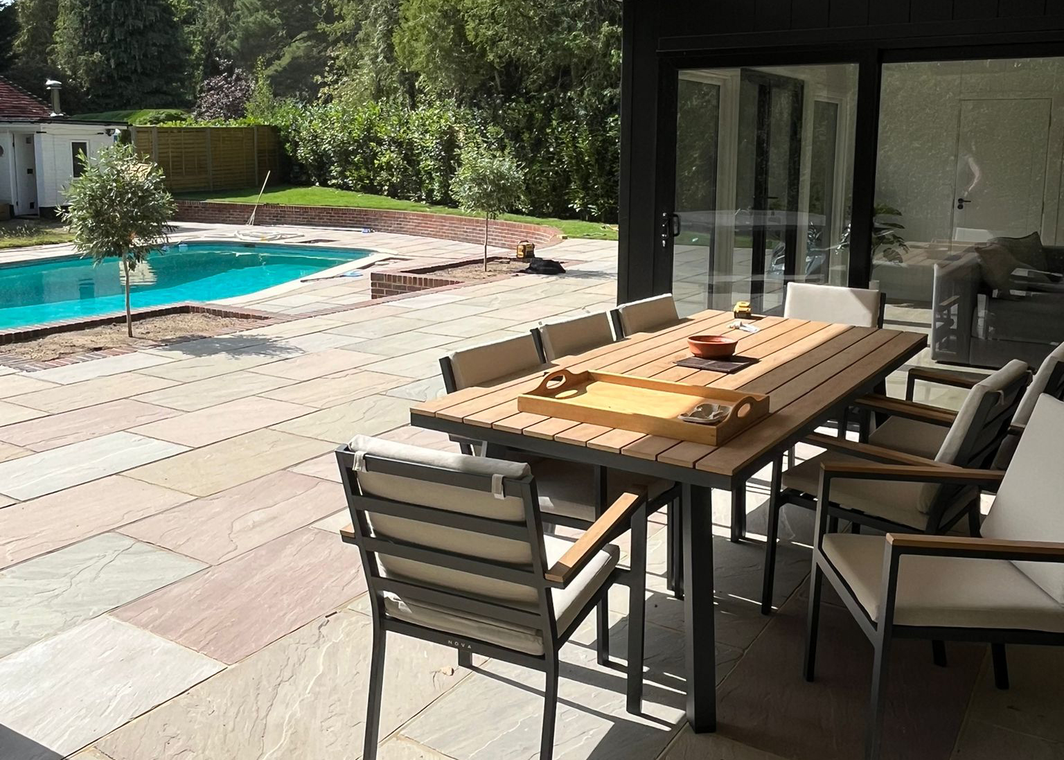 Luxury patio and outdoor dining area with porcelain paving and swimming pool in Sussex
