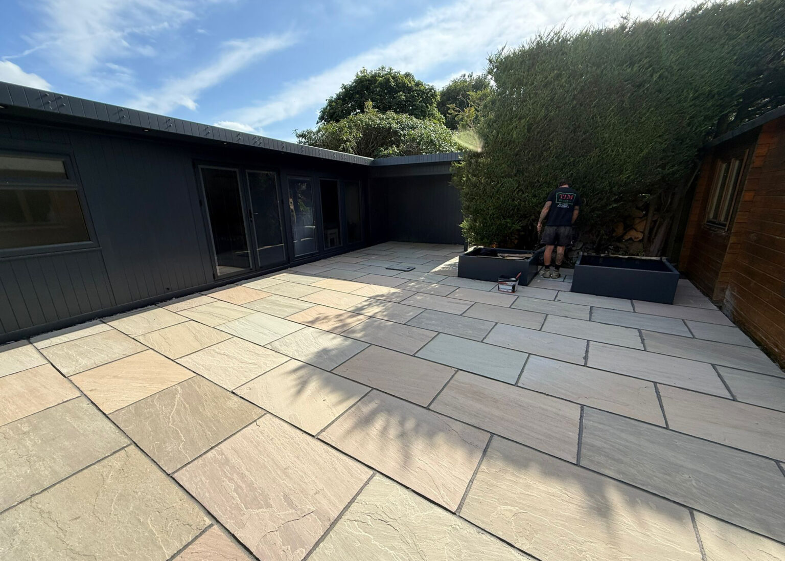 Porcelain paving patio with contemporary planters and garden room
